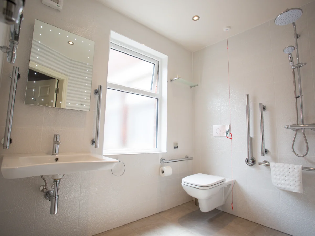 Barrierefreies Badezimmer mit ebenerdiger Dusche, Haltegriffen und unterfahrbarem Waschbecken