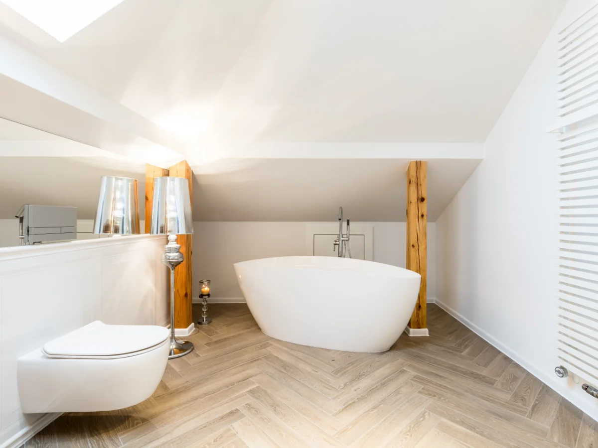 Modernes Badezimmer im Dachgeschoss mit freistehender Badewanne und Holzoptik-Boden