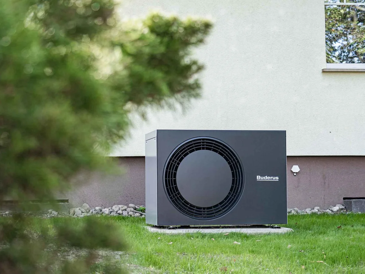Moderne Wärmepumpe von Buderus installiert im Garten eines Wohnhauses